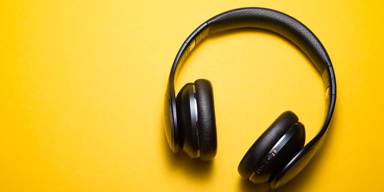 A pair of black headphones on a yellow background.